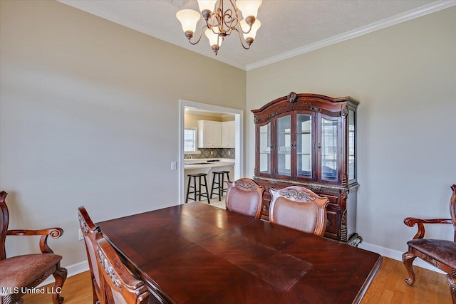 dining space with a chandelier, ornamental molding, baseboards, and light wood-style floors