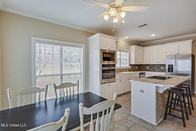 kitchen featuring visible vents, appliances with stainless steel finishes, a center island, a sink, and backsplash