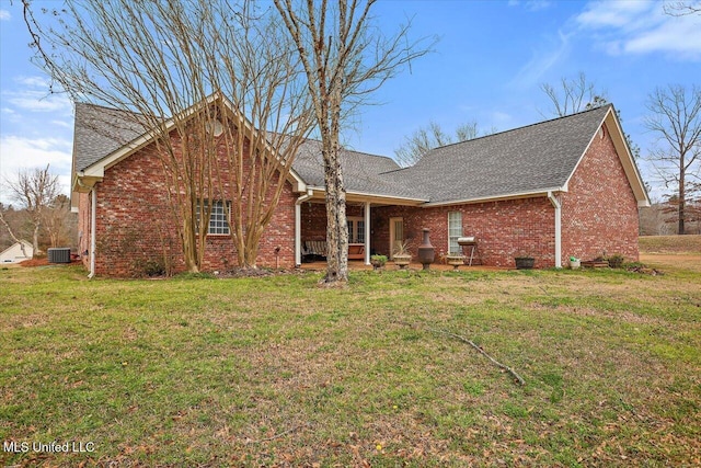 view of front of property featuring central air condition unit, roof with shingles, a front lawn, and brick siding