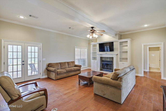 living area featuring a fireplace, wood finished floors, visible vents, ornamental molding, and french doors