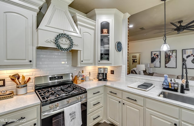 513 Willow Valley Cir, Brandon, MS 39047 - kitchen featuring gas stove, ceiling fan, tasteful backsplash, glass insert cabinets, and light countertops