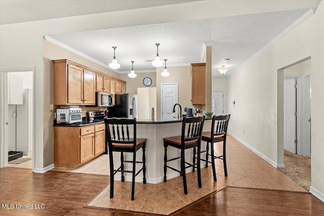 kitchen featuring sink, a textured ceiling, a breakfast bar, appliances with stainless steel finishes, and ornamental molding