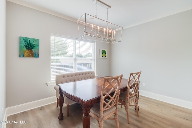 dining space with light wood-type flooring, baseboards, crown molding, and an inviting chandelier