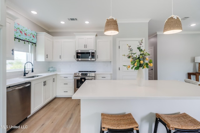 kitchen with appliances with stainless steel finishes, a sink, decorative backsplash, visible vents, and ornamental molding