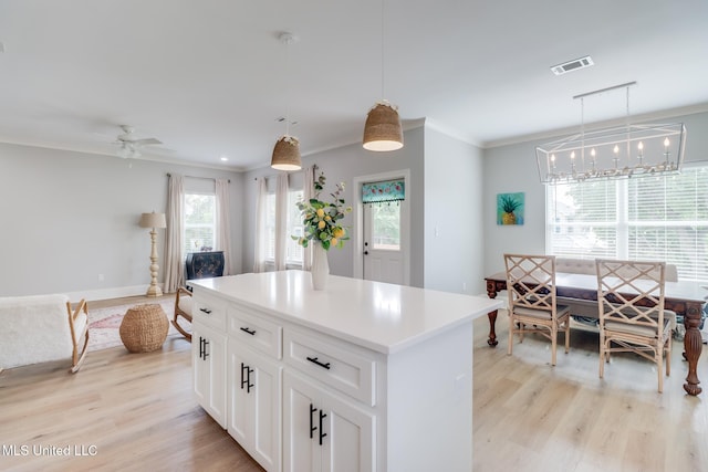 kitchen with visible vents, ornamental molding, light wood finished floors, and a kitchen island