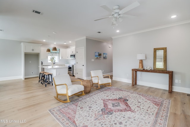 sitting room with crown molding, a ceiling fan, baseboards, and visible vents