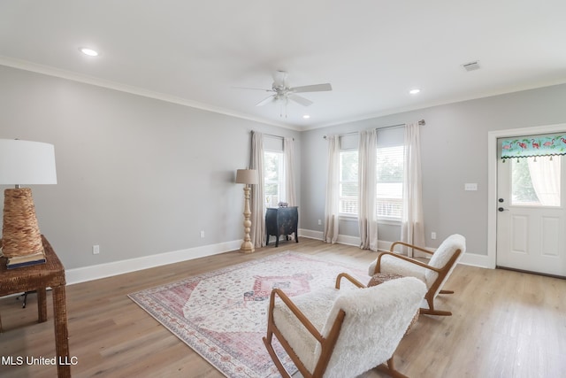 living area featuring visible vents, a ceiling fan, light wood finished floors, and a wealth of natural light