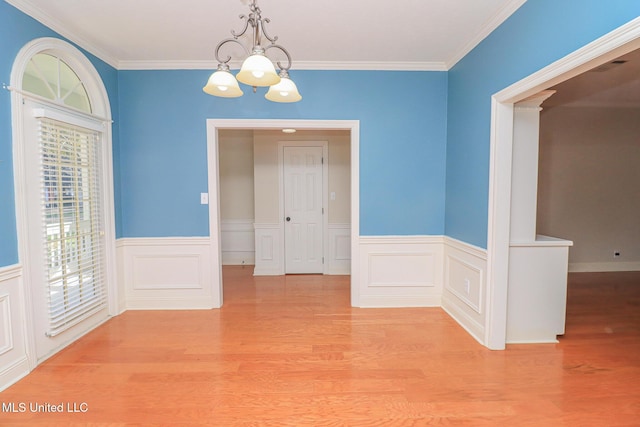 unfurnished dining area featuring light hardwood / wood-style floors, ornamental molding, and an inviting chandelier