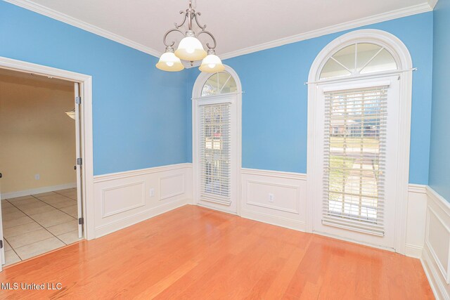 tiled empty room with crown molding and a chandelier