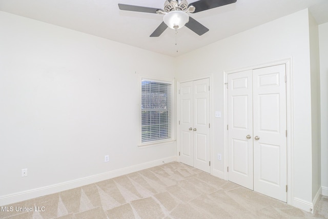 unfurnished bedroom featuring ceiling fan, light colored carpet, and multiple closets