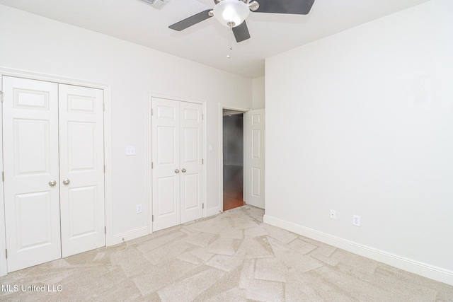 unfurnished bedroom featuring multiple closets, ceiling fan, and light colored carpet