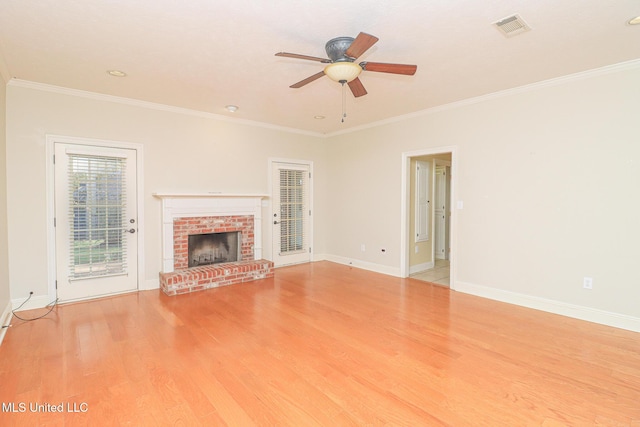 unfurnished living room featuring ceiling fan, light wood-type flooring, crown molding, and a brick fireplace