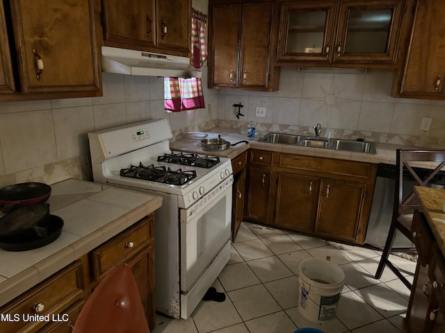 kitchen with tasteful backsplash, sink, tile counters, and gas range gas stove