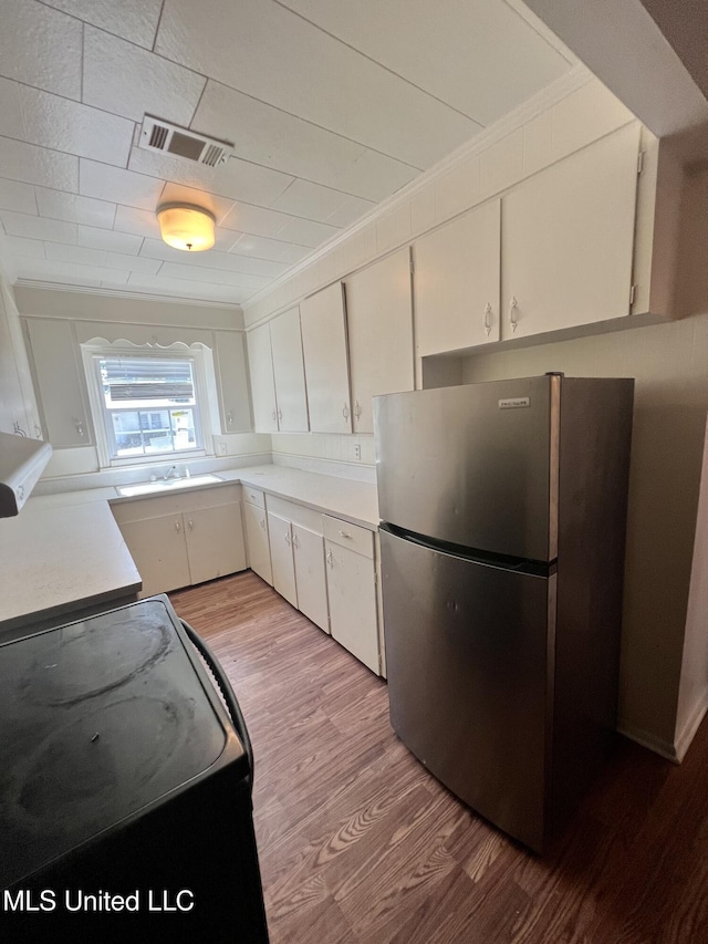 802 Farmer St, Cleveland, MS 38732 - kitchen with freestanding refrigerator, wood finished floors, light countertops, black electric range oven, and white cabinets