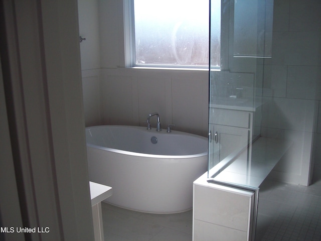 bathroom featuring tile patterned flooring, vanity, a bathtub, and tile walls