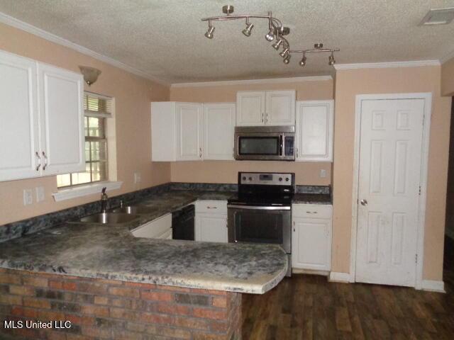 6301 Pioneer Trl, Moss Point, MS 39562 - kitchen featuring appliances with stainless steel finishes, white cabinets, dark wood-style floors, crown molding, and a textured ceiling
