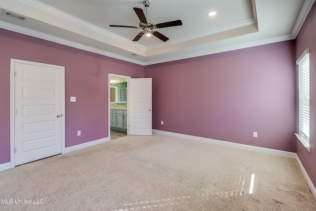 empty room with ornamental molding, a healthy amount of sunlight, and a raised ceiling