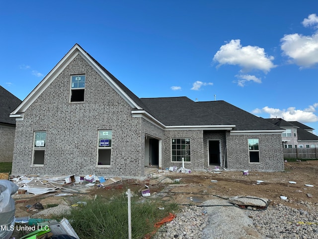 view of front of property featuring brick siding and a shingled roof