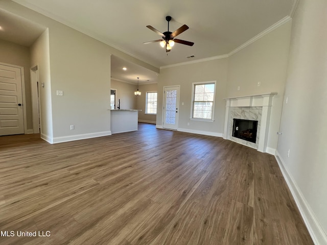 unfurnished living room with a high end fireplace, ornamental molding, ceiling fan with notable chandelier, and wood-type flooring