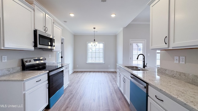 kitchen with white cabinetry, stainless steel appliances, sink, ornamental molding, and a chandelier