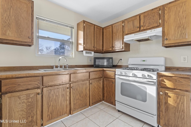 kitchen featuring light tile patterned flooring, a sink, white gas range oven, under cabinet range hood, and black microwave