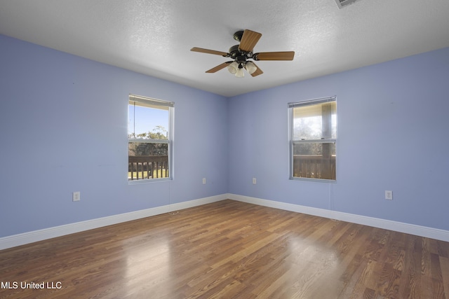 unfurnished room featuring baseboards, a textured ceiling, a healthy amount of sunlight, and wood finished floors