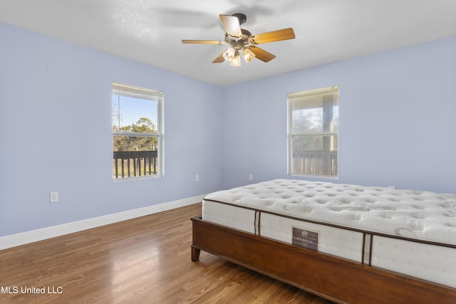 bedroom featuring ceiling fan, baseboards, and wood finished floors