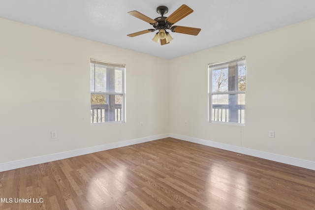 unfurnished room featuring wood finished floors, a healthy amount of sunlight, and baseboards