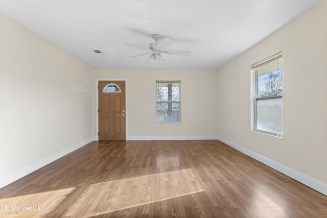 interior space featuring a ceiling fan, visible vents, wood finished floors, and baseboards