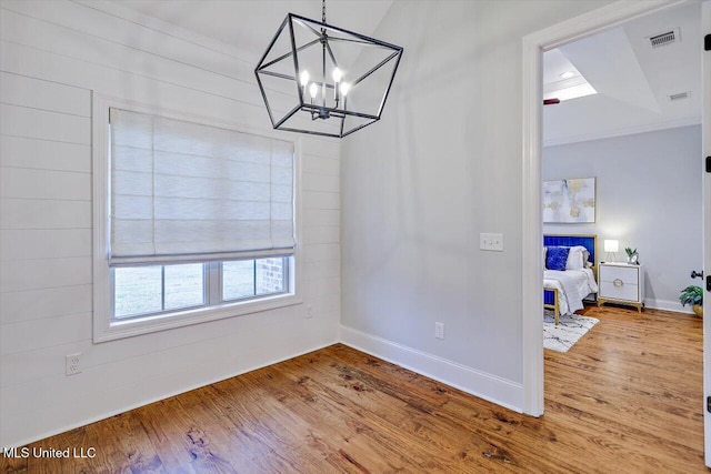 dining room with a notable chandelier, wood-type flooring, and wooden walls