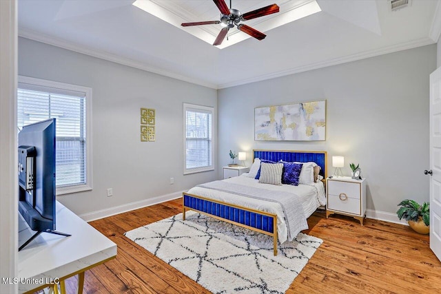 bedroom with ceiling fan, wood-type flooring, crown molding, and multiple windows