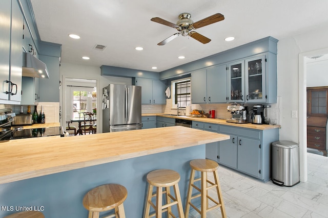 kitchen featuring extractor fan, appliances with stainless steel finishes, kitchen peninsula, and blue cabinets