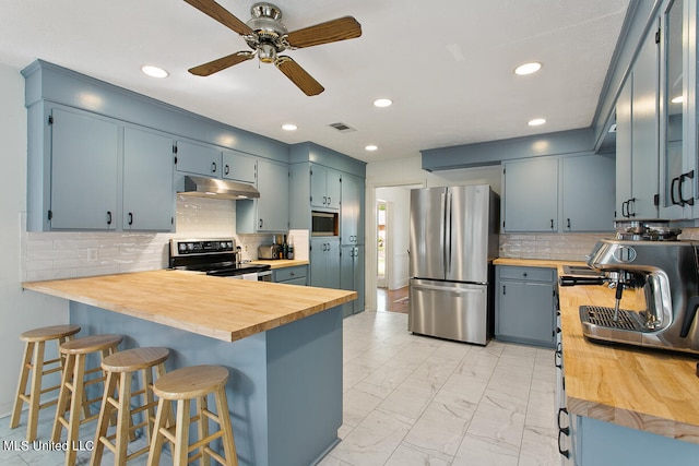 kitchen with decorative backsplash, kitchen peninsula, blue cabinetry, appliances with stainless steel finishes, and ceiling fan