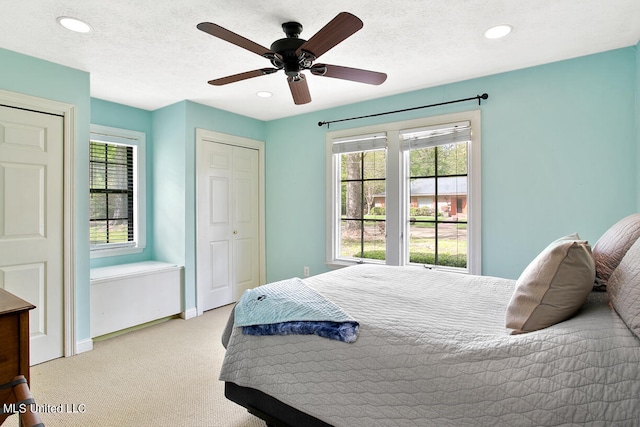 carpeted bedroom featuring multiple windows, a textured ceiling, and ceiling fan