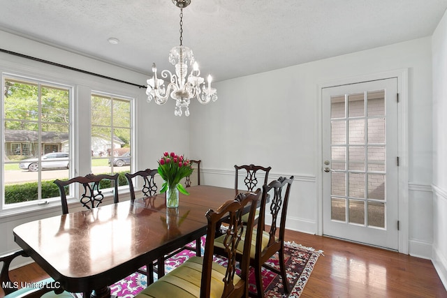 dining space with a notable chandelier, a textured ceiling, and hardwood / wood-style floors