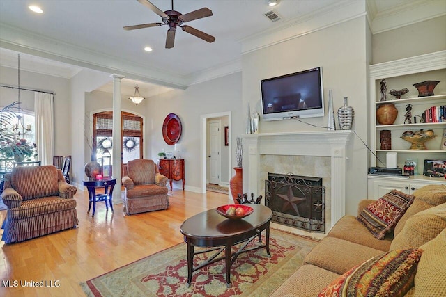 living room with ceiling fan, light hardwood / wood-style floors, ornamental molding, and a tile fireplace