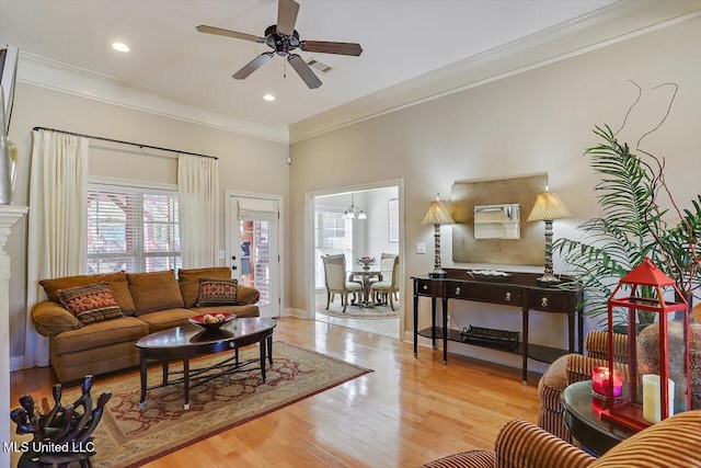 living room featuring ceiling fan with notable chandelier, light hardwood / wood-style floors, and ornamental molding