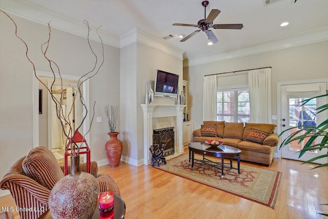 living room with ceiling fan, light wood-type flooring, and crown molding