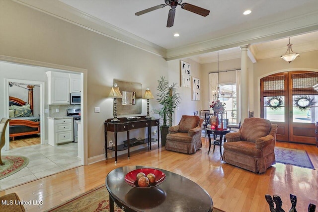 living room featuring ceiling fan, light hardwood / wood-style floors, and crown molding