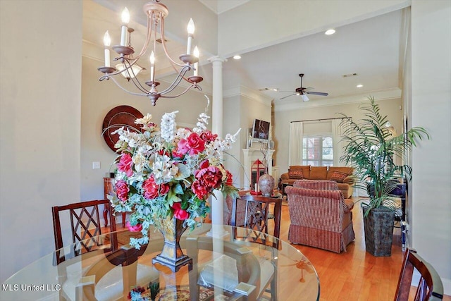 dining room with hardwood / wood-style floors, ceiling fan with notable chandelier, ornamental molding, and decorative columns