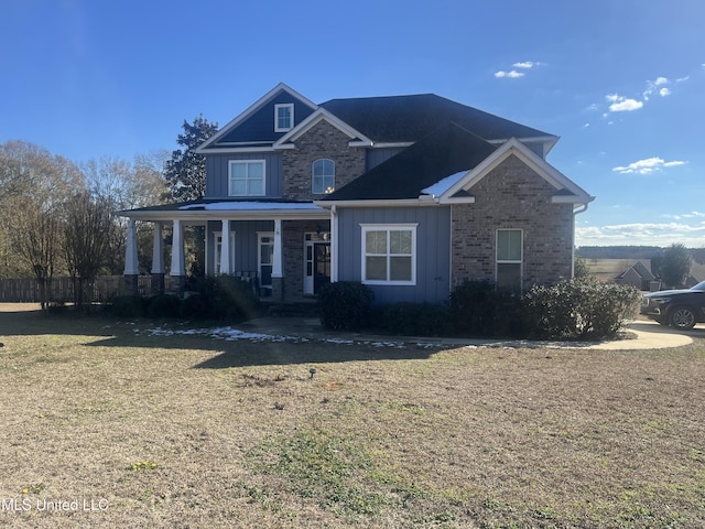 view of front facade with board and batten siding, a front yard, and brick siding