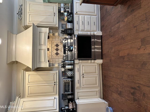 kitchen with cream cabinetry, wood walls, and tasteful backsplash