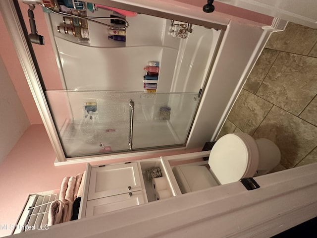 bathroom featuring an enclosed shower and toilet