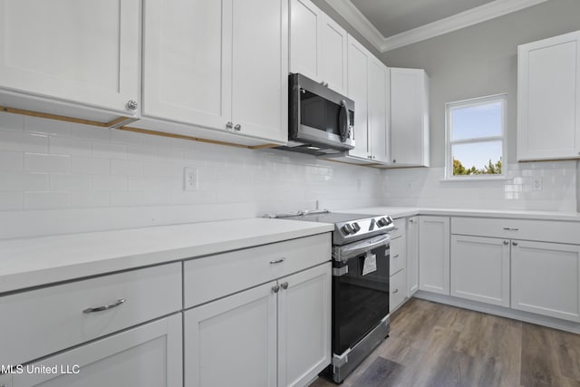 kitchen featuring appliances with stainless steel finishes, ornamental molding, decorative backsplash, light countertops, and white cabinetry