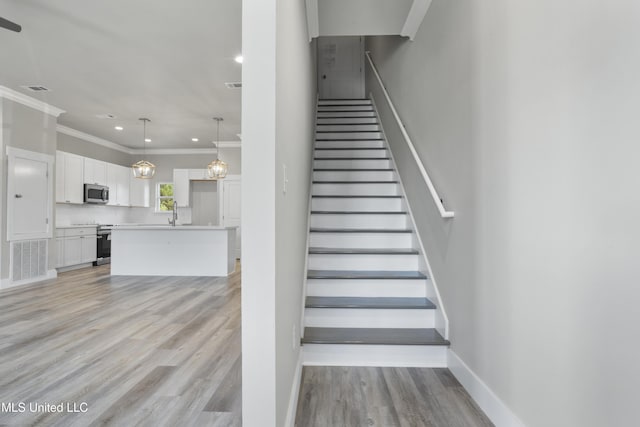 stairs featuring ornamental molding, wood finished floors, baseboards, and recessed lighting