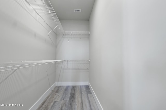 walk in closet with wood finished floors