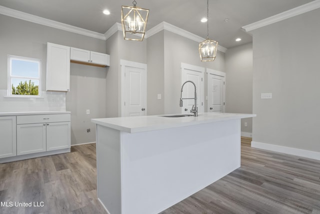 kitchen featuring a chandelier, a sink, ornamental molding, light wood-type flooring, and white cabinets