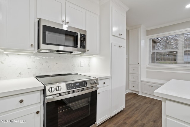 kitchen with tasteful backsplash, crown molding, appliances with stainless steel finishes, dark hardwood / wood-style flooring, and white cabinets