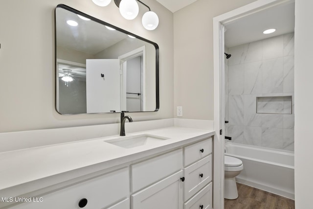 full bathroom with vanity, tiled shower / bath combo, wood-type flooring, and toilet