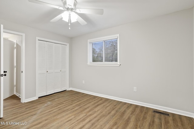 unfurnished bedroom with hardwood / wood-style flooring, ceiling fan, and a closet